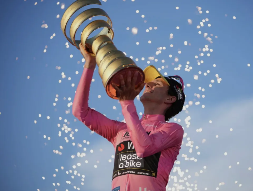 A race winner in the pink jersey celebrating with the trophy
